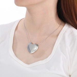 Gros plan d'un collier avec pendentif cœur argenté porté par un mannequin sur fond blanc
