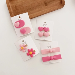 Detail of matte pink hair clips set featuring heart, flower, and bow shapes on display cards