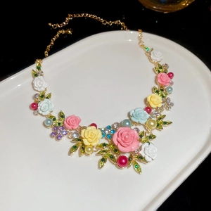 Close-up of a floral necklace with colorful resin roses and pearls on a white tray