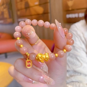 Close-up of sunstone beaded bracelet with gold PiXiu and NaFu blessing charm