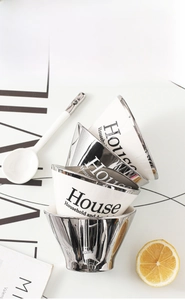 Close-up of stacked ceramic conical bowls with silver mirror finish and matching white spoon