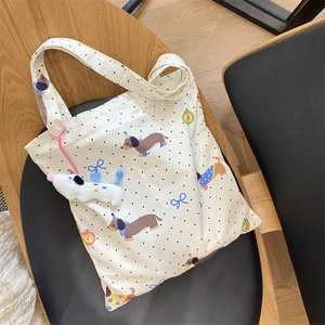 Detail of dachshund printed white canvas tote bag with plush charm on a black chair