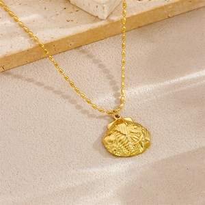 Gold stainless steel necklace with seashell pendant on decorative beige stone blocks