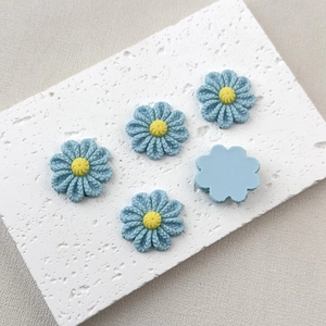 Macro detail of blue resin flower charms with yellow center for DIY crafts decoration