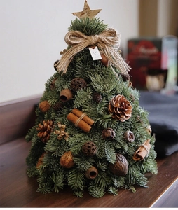 Close-up of mini Christmas tree with pine cones, cinnamon sticks, and a wooden star topper