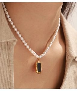Detail of freshwater pearl necklace featuring a gold square pendant with black inlay