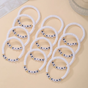 Detail of white polymer clay bracelets with BE KIND letter beads and gold metal spacers