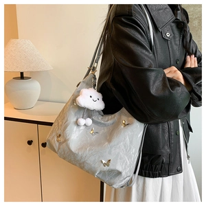 Detail of silver tote bag with golden butterflies and white cloud plush charm detail