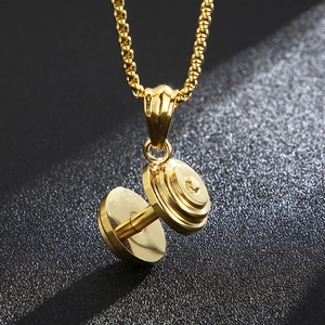 Polished gold dumbbell pendant necklace in stainless steel on a dark textured surface