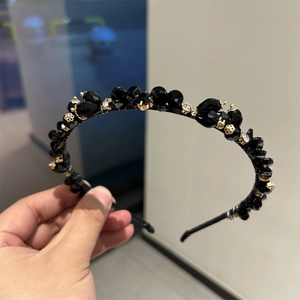 Detail of luxury handmade headband with black crystals, rhinestones and gold flowers