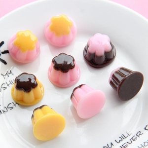 Miniature resin pudding charms in pink and yellow on a white plate with pink background