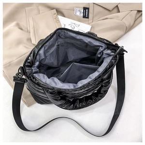 Top view of black quilted puffer bag showing grey interior lining and zipper pocket