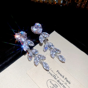 Detailed close-up of zircon tassel earrings with heart and leaf-shaped crystals on velvet