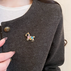 Detailed close-up of a horse brooch with colorful rhinestones on a dark wool coat