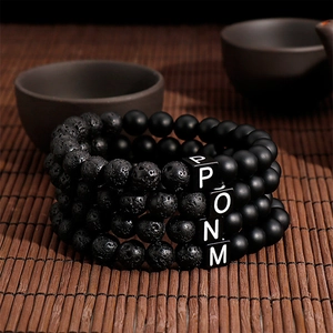 Macro detail of lava stone bracelets with letter beads on a bamboo mat background