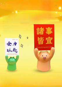 Detail of cute resin pig and frog figurines holding motivational signs on a desk