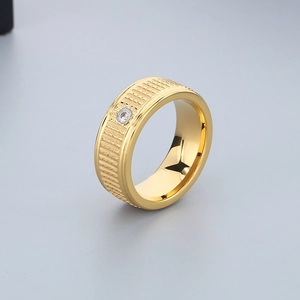 Detailed view of wide gold titanium steel ring featuring stepped texture and single zircon