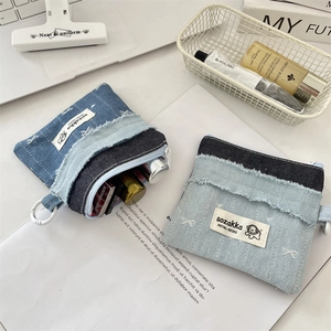 Nahaufnahme der Denim-Münztaschen mit ausgefransten Kanten und Reißverschluss für Kosmetik