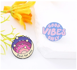 Detail of round enamel pins with 'Best for you' and 'GOOD VIBES ONLY' inspirational text
