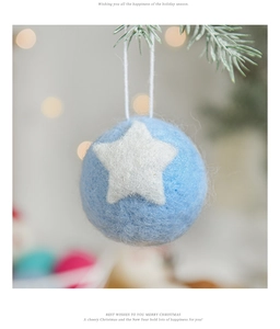 Close-up of blue wool felt Christmas ball with white stars hanging on a festive tree branch