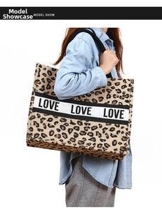 Detail of large leopard print jute tote bag with LOVE logo held by model in denim shirt