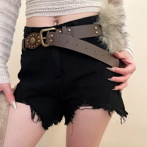 Détail d'une ceinture en cuir vintage avec rivets en bronze et pompon en fausse fourrure