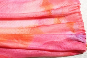 Détail du tissu en maille tie-dye rose et orange respirant avec structure fine