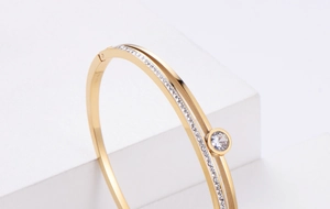 Macro side view of golden double-layer hollow bangle with pavé crystals and round centerpiece