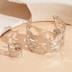 Detail view of silver ginkgo leaf cuff bracelet and ring set on minimalist stone decor