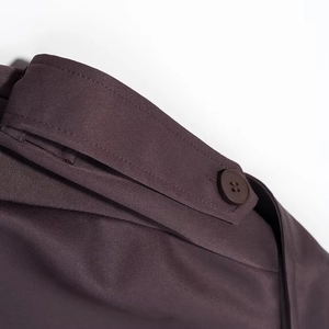 Détail d'un trench-coat violet foncé montrant l'épaulette boutonnée et le tissu sergé