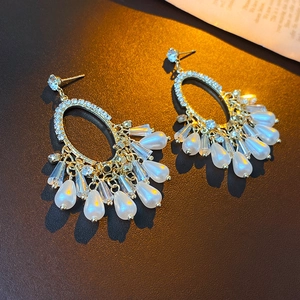 Detail of vintage gold earrings with rhinestones and white pearl fringe tassels