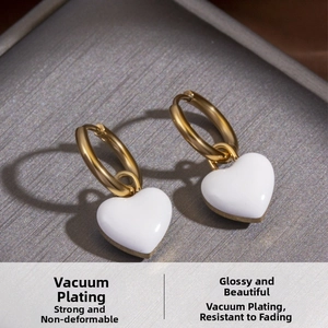 Detailed macro shot showing the gold heart charm earrings with vacuum plating finish