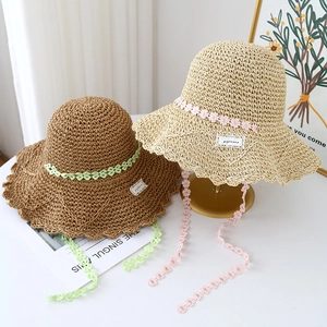 Straw sun hats with floral lace ribbons in dark brown and beige on golden stands