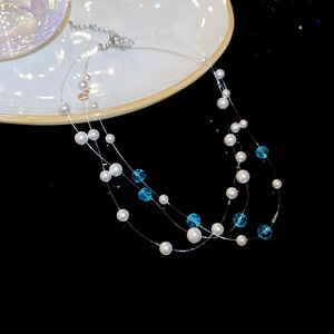 Detailed close-up of multi-layer pearl and blue crystal bead necklace on black background