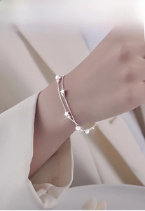 Close-up of double-layer silver star bracelet on wrist with matte star and bead charms