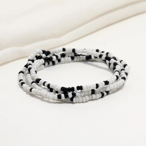 Close-up of double-layered black and white seed bead chain on soft white fabric