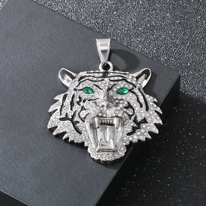 Macro shot of silver tiger head pendant with white crystals and green stone eyes