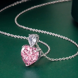Détail du collier argenté avec pierre poire et gemme rose en forme de cœur brillant