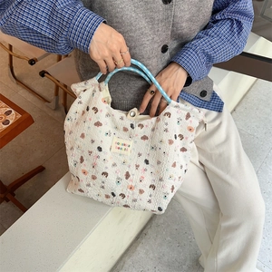 Detail of waffle texture cartoon dog tote bag with blue checkered handles and logo