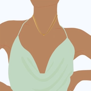 Close-up of double-layer gold snake chain and beaded pendant necklace on female neck