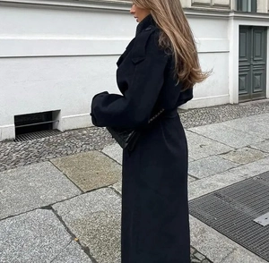 Vue détaillée d'un long manteau noir en laine avec revers à deux boutons et coupe ample
