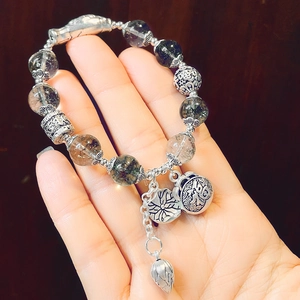 Detail view of retro beaded bracelet with silver metal charms and translucent crystals