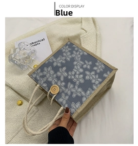 Close-up of blue floral canvas tote with white rope handles and decorative wooden button