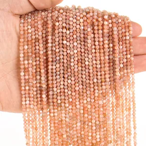 Macro detail of 3mm orange-pink faceted natural stone round beads held in palm for DIY jewelry