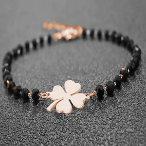Macro view of black beaded bracelet featuring a rose gold clover pendant and clasp