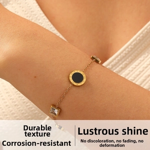 Detail of gold plated bracelet with roman numeral charm and square zircon on model wrist