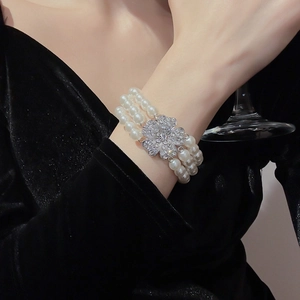 Close-up of elegant multi-layered white pearl bracelet with sparkling clover diamond clasp