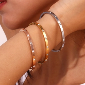 Close-up of minimalist gold and silver bangles with embedded round cubic zirconia stones