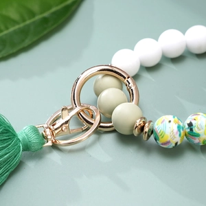 Silicone beaded keychain bracelet with green tassels and golden metal hardware