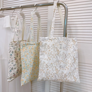 Set of three floral and rabbit print canvas tote bags hanging on a steel rack
